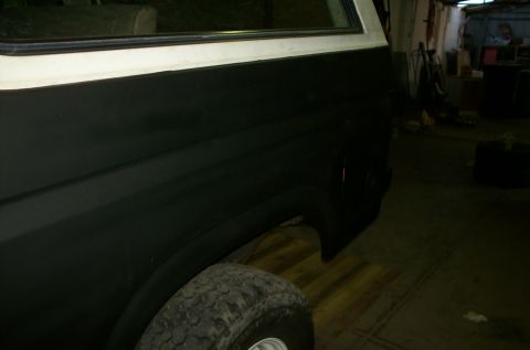 1981 Ford Bronco - Side view of a 1981 Ford Bronco's rear section, showing the black paint job and tire.