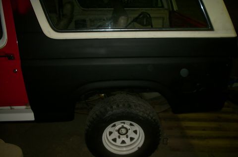 1981 Ford Bronco - The side of a Ford Bronco is shown, with a red door and black painted body panels.