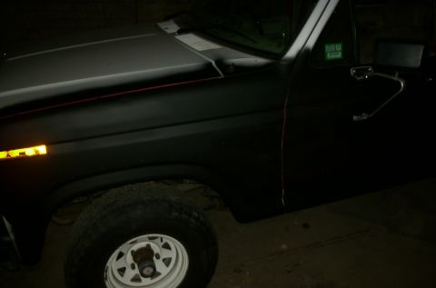 1981 Ford Bronco - The front quarter panel and door of a black Ford Bronco are visible in this dimly lit image.