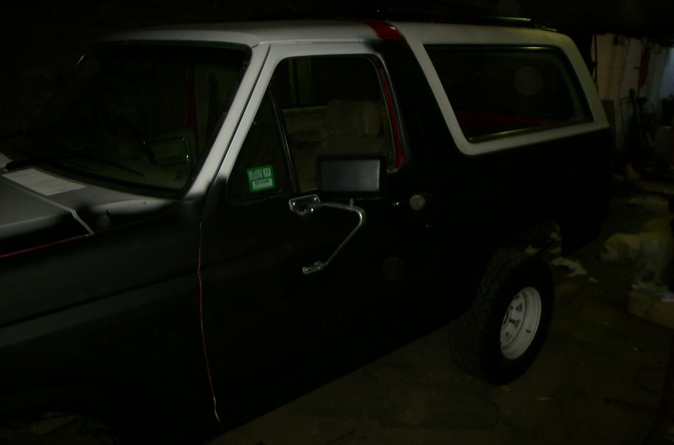 Black Ford Bronco with white roof and red stripe, side view
