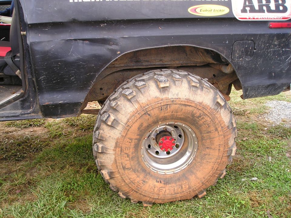 Muddy off-road tire on a black vehicle, showing part of the door and fender