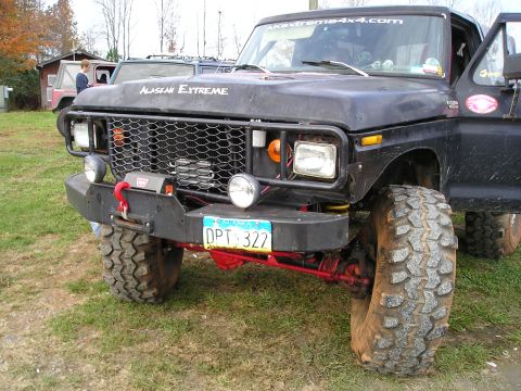 1996 Ford Bronco - Modified black Ford truck with "ALASKAN EXTREME" graphics and large off-road tires.