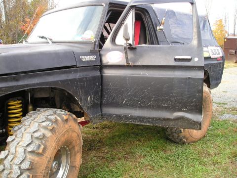 1996 Ford Bronco - A black Ford Bronco with a lifted suspension and aggressive tires sits on grassy terrain.