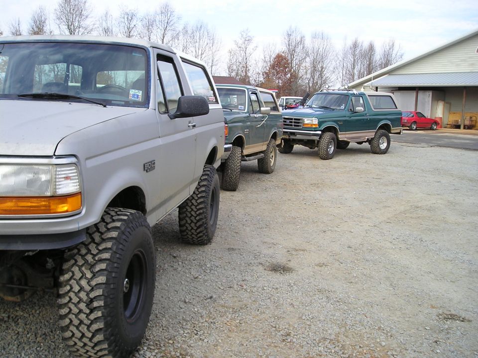 Three lifted Ford Broncos parked in a gravel lot