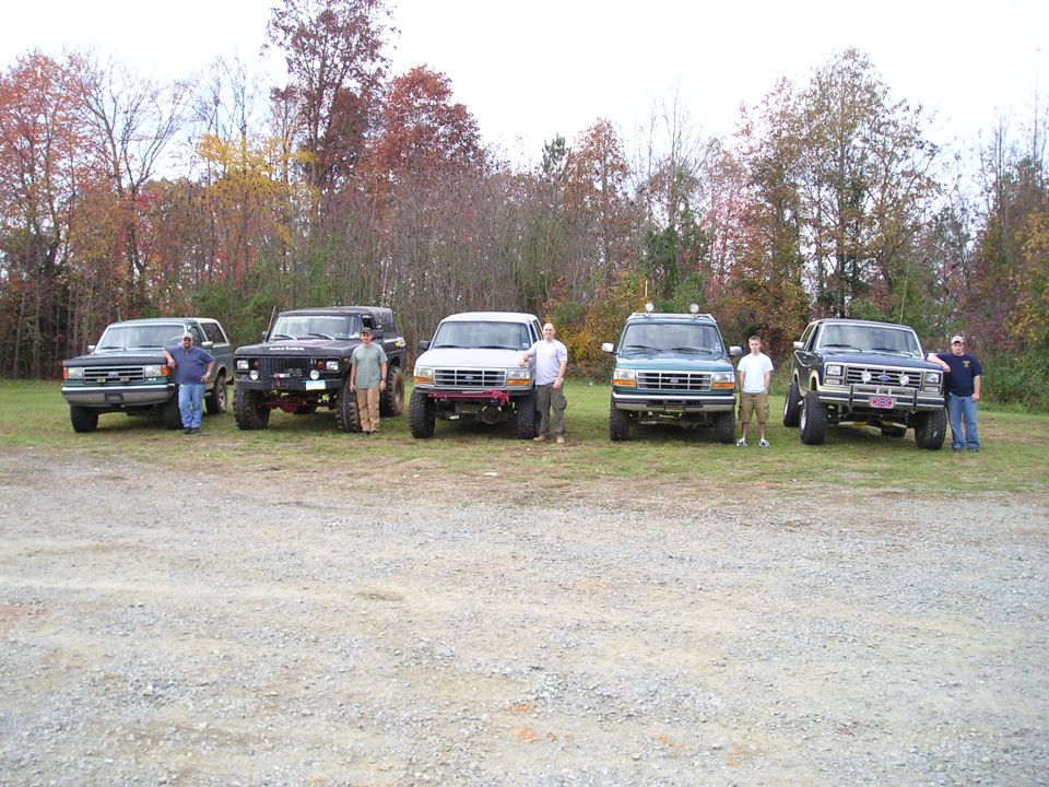 Five SUVs and trucks parked in a lot with people standing by them
