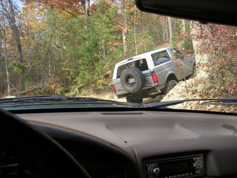 1996 Ford Bronco - A Ford Bronco navigates a wooded trail with autumn foliage.