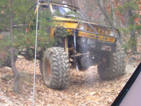 1996 Ford Bronco - A modified 1996 Ford Bronco navigates a wooded trail with large, aggressive tires.