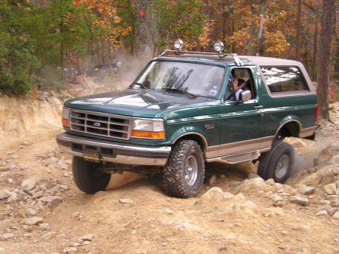 1996 Ford Bronco - 1996 Ford Bronco tackling a challenging off-road course with a second vehicle in the background.