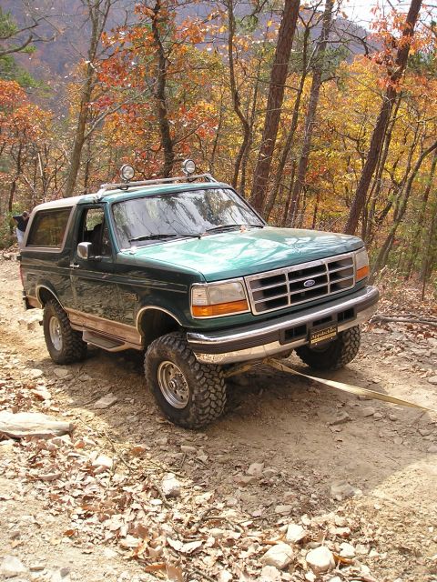 1996 Ford Bronco - A 1996 Ford Bronco navigates a wooded trail during autumn.