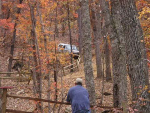 1996 Ford Bronco - A 1996 Ford Bronco navigates a steep, wooded incline during autumn.