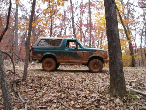 1996 Ford Bronco - A muddy 1992 Ford Bronco sits in a wooded area during autumn.