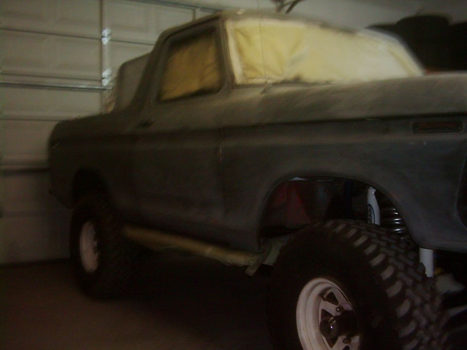 1978 Ford Bronco body in primer, parked indoors with windows taped