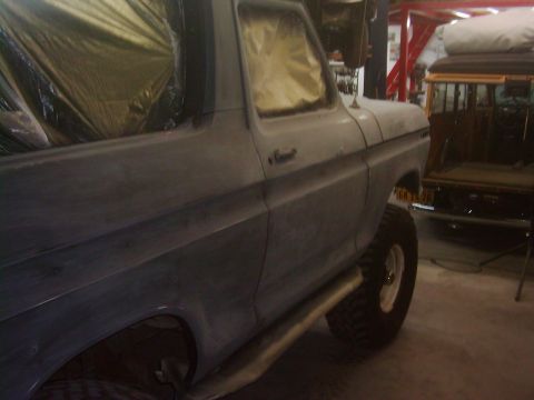 1978 Ford Bronco - This SUV is undergoing preparation for a new paint job, with its windows covered in protective tape.
