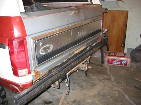 1985 Ford Bronco - The rear of a Ford Bronco shows significant rust on the bumper and lower body panels.