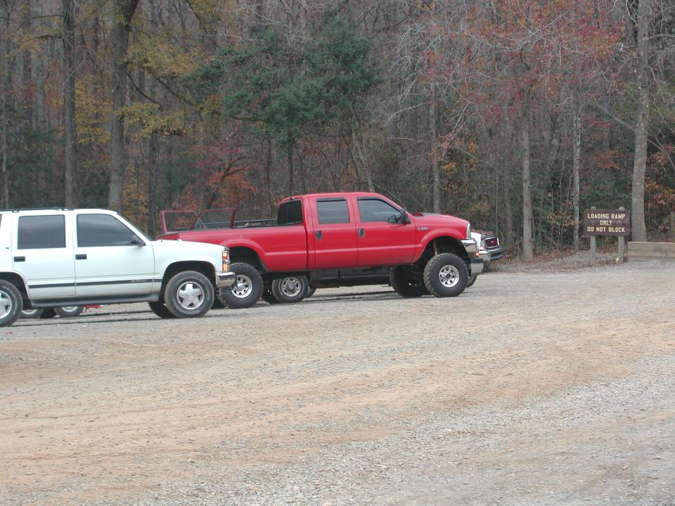 Red six-wheeled pickup truck parked next to a white SUV