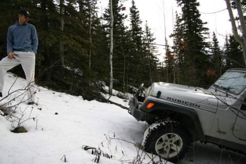 2003 Jeep TJ - A man stands next to a silver Jeep Wrangler Rubicon on a snow-covered forest trail.