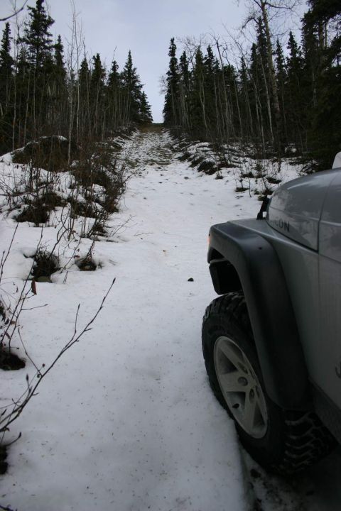 2003 Jeep TJ - A silver Jeep TJ navigates a snow-covered path through a forest.