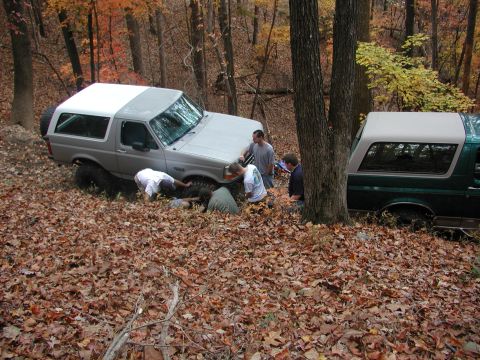 1985 Ford Bronco - Two Ford Broncos are seen in a wooded area, with a group of people attending to the silver Bronco.