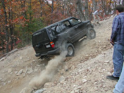 1985 Ford Bronco - A black SUV navigates a steep, rocky incline during an off-road excursion.