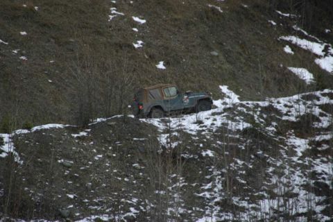 2003 Jeep TJ - A Jeep Wrangler sits on a dirt path covered in snow and sparse vegetation on a hillside.