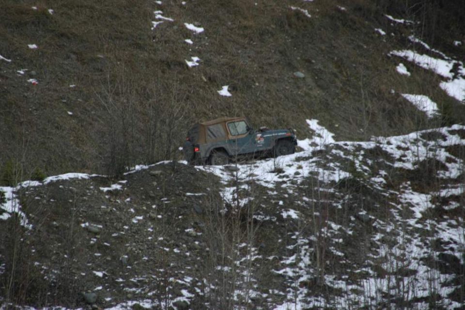 Jeep Wrangler parked on a snowy, wooded hillside