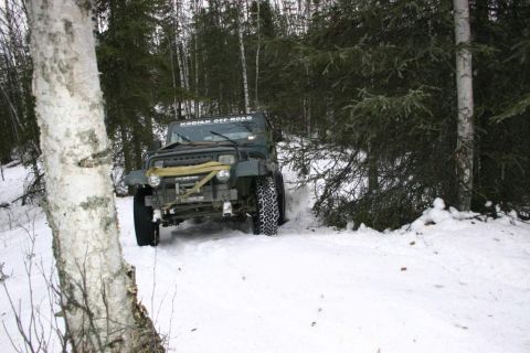 2003 Jeep TJ - A dark green Jeep Wrangler navigates a snowy forest path, its front end visible through the trees.