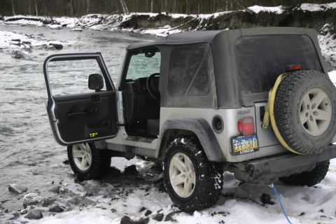 2003 Jeep TJ - A silver 2003 Jeep TJ is parked by a river in the snow, with the driver's door open.