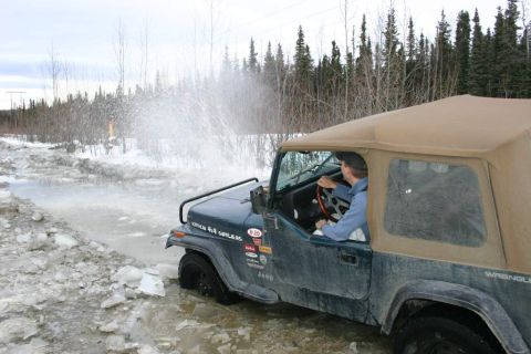 2003 Jeep TJ - A Jeep Wrangler navigates a water-filled, icy path with trees in the background.