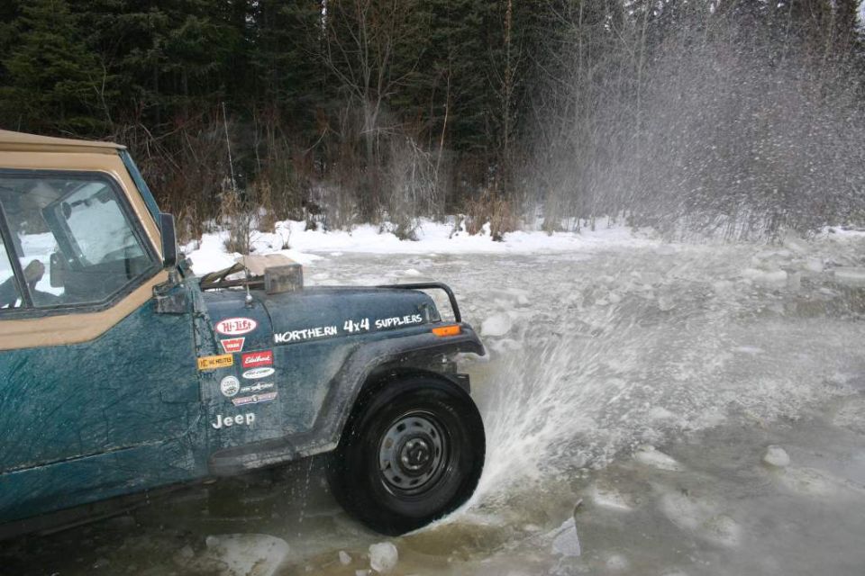 Green Jeep splashing through icy water, with Northern 4x4 Suppliers sticker