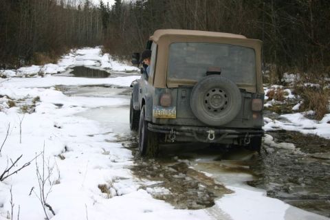 2003 Jeep TJ - A 2003 Jeep Wrangler navigates a challenging icy and snowy trail, demonstrating its off-road capabilities.