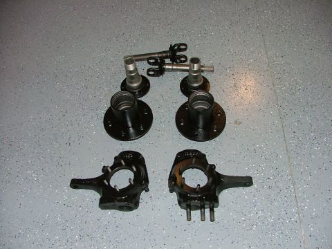 1988 Ford Bronco - A set of automotive front wheel hubs and spindles are displayed on a garage floor.