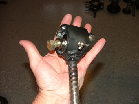 1988 Ford Bronco - A hand holds a black automotive part with visible metal components and a threaded shaft.