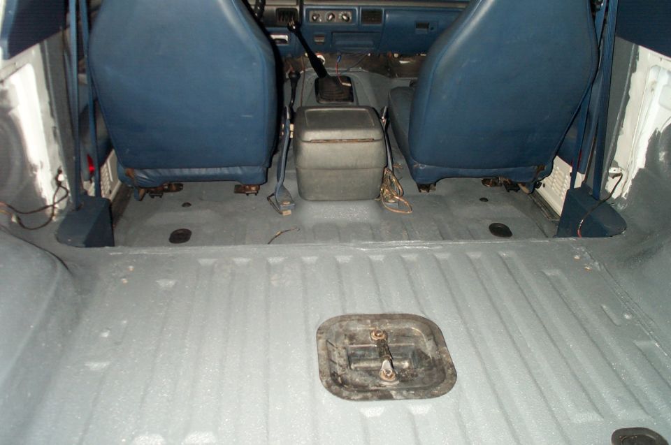 Bronco interior with blue seats, gray painted floor, and black floor access panel