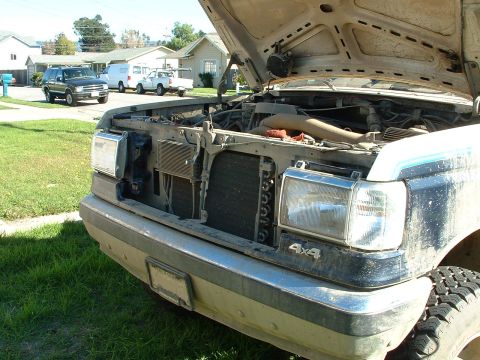 1990 Ford Bronco - Front view of a 1990 Ford Bronco with the hood up, parked in a residential area.