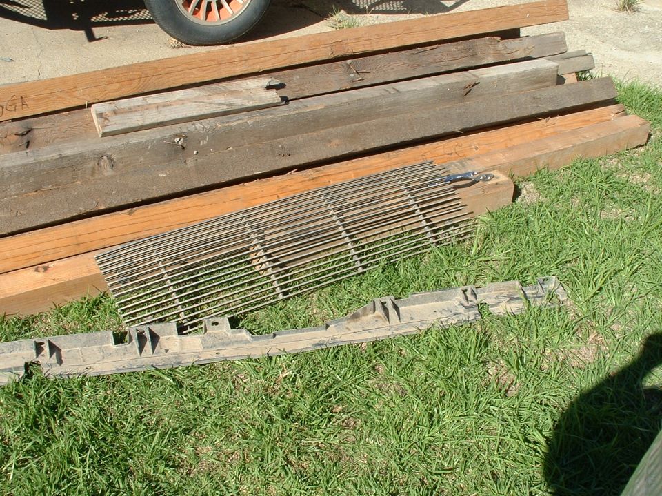 Ford Bronco grille and plastic bumper piece on grass next to lumber