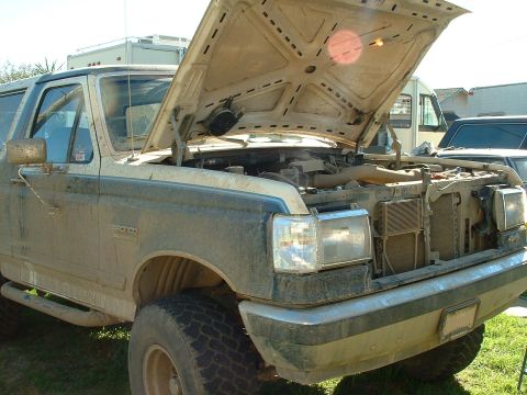 1990 Ford Bronco - A dirty 1990 Ford Bronco sits with its hood open, revealing the engine bay.