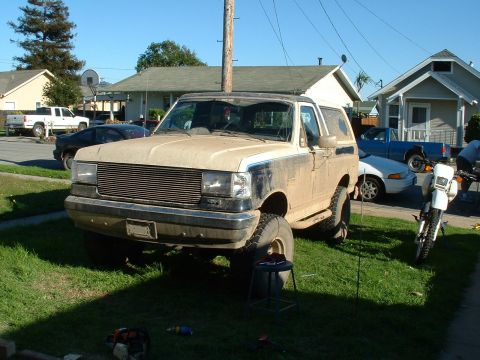 1990 Ford Bronco - This lifted 1990 Ford Bronco is parked on a grassy lawn with other vehicles in the background.
