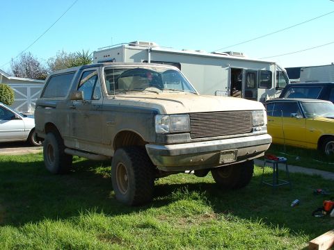 1990 Ford Bronco - This 1990 Ford Bronco is parked outside next to an RV and a yellow car.
