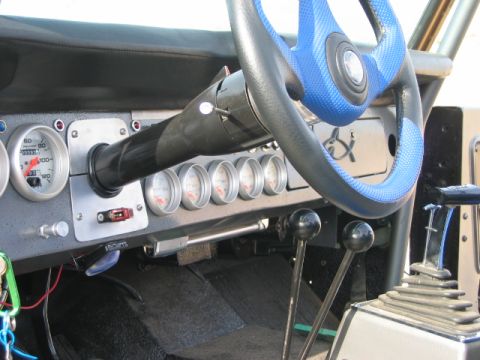 1985 Ford Bronco - The interior features a custom steering wheel and numerous gauges, with multiple gear shifters visible.