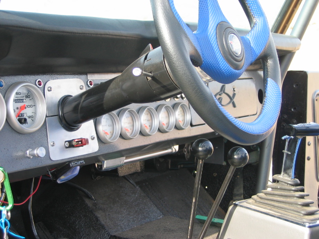 Custom interior dash with blue steering wheel, speedometer, row of gauges, and twin shift levers