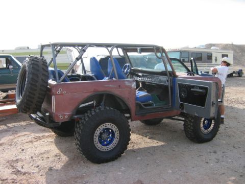 1985 Ford Bronco - This heavily modified off-road vehicle features a custom roll cage and large tires, with other vehicles visible in the background.