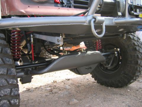 1985 Ford Bronco - Close-up view of the front suspension and undercarriage of a modified off-road vehicle, heavy-duty components and large tires.