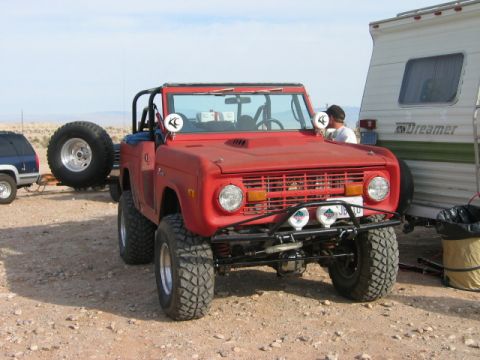 1985 Ford Bronco - This red Ford Bronco, likely from the mid-1970s, is equipped for off-road adventures and is parked next to a trailer.