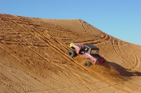 1974 Ford Bronco - Remote control rock crawler navigates a steep sand dune, leaving tire tracks.