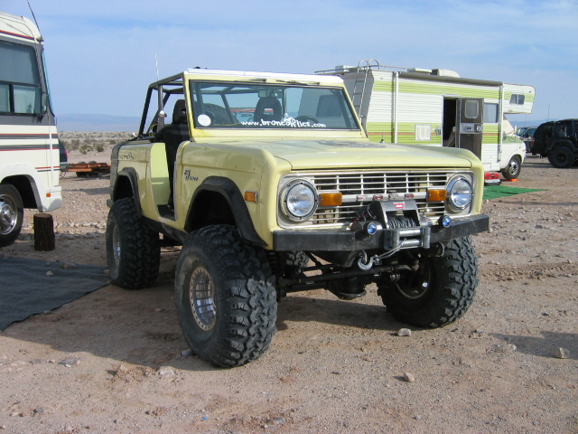 Pale yellow lifted early Ford Bronco with winch bumper on dirt lot