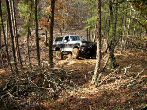 1995 Ford Bronco - A lifted Ford Bronco navigates a wooded trail in the fall.