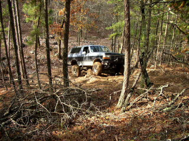 Two-tone gray and black Ford Bronco with lifted suspension driving off-road