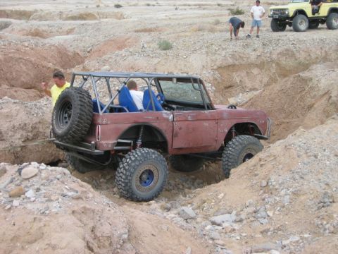 1985 Ford Bronco - This heavily modified Bronco navigates a challenging off-road course, while another vehicle waits nearby.
