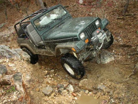 1995 Ford Bronco - Jeep Wrangler tackling a challenging off-road course with steep inclines and obstacles.