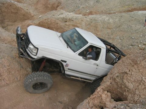 1985 Ford Bronco - This modified SUV is navigating a challenging off-road course with steep inclines and rocky obstacles.